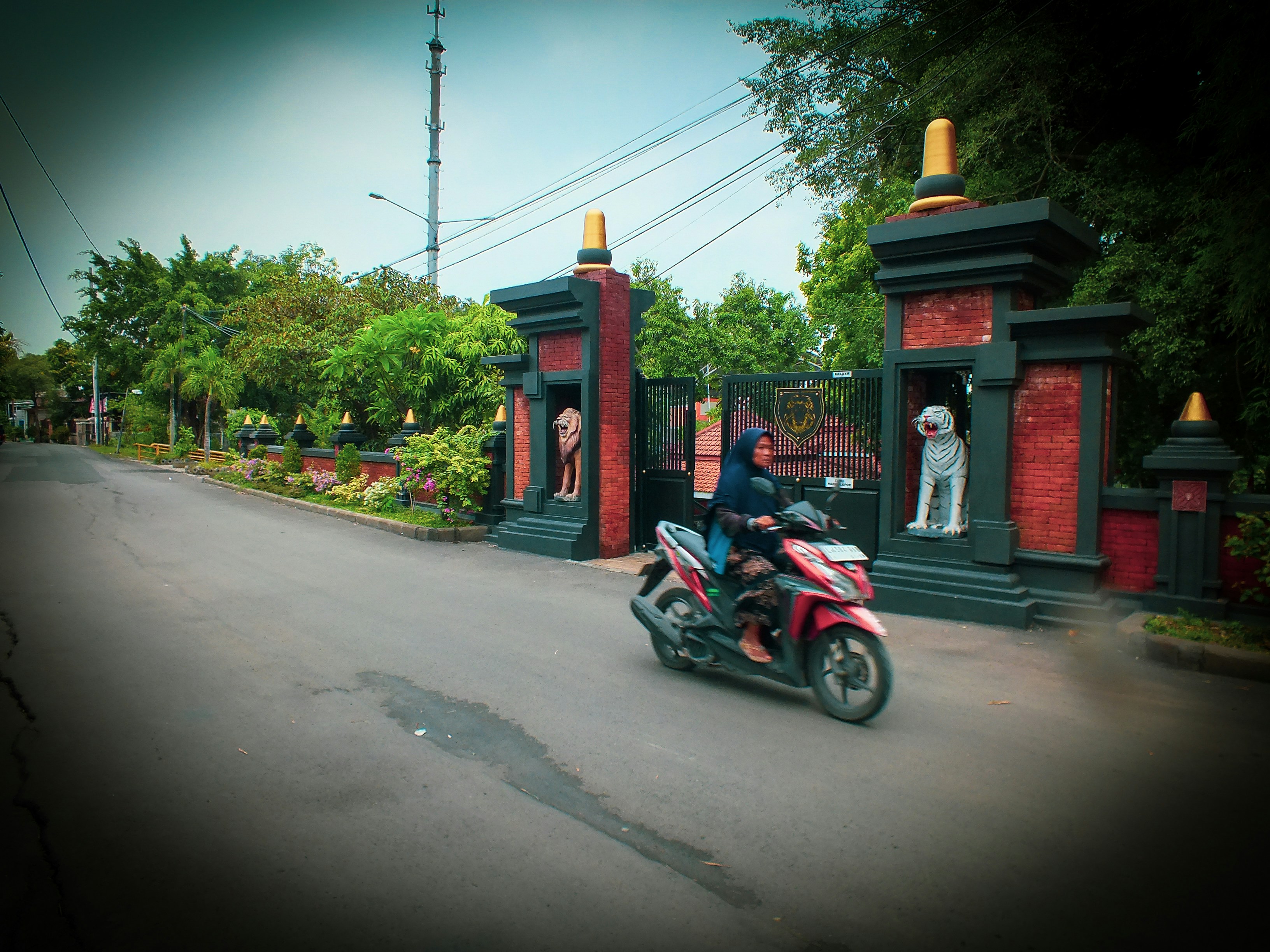 A man riding a red motorcycle down a street